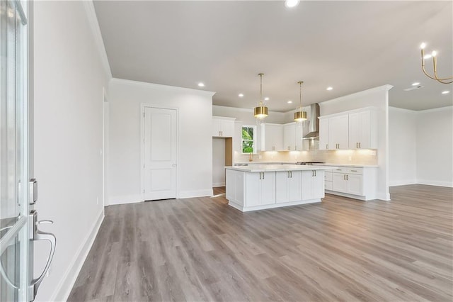 kitchen with wall chimney range hood, a center island, white cabinetry, and light hardwood / wood-style flooring