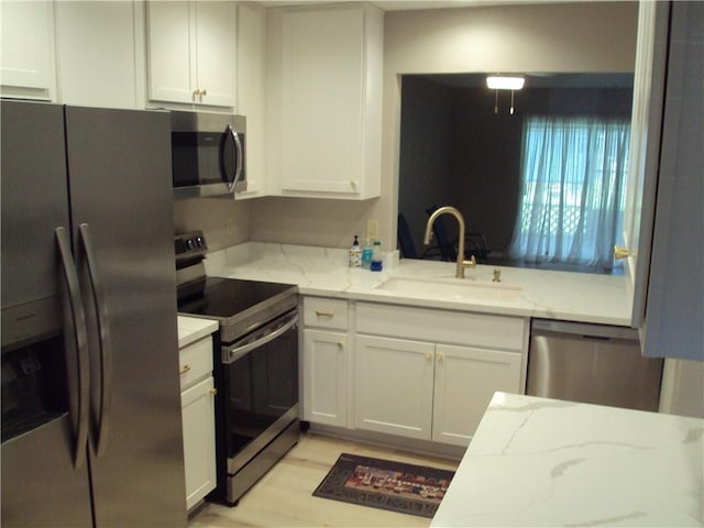 kitchen featuring sink, light hardwood / wood-style floors, light stone counters, and stainless steel appliances