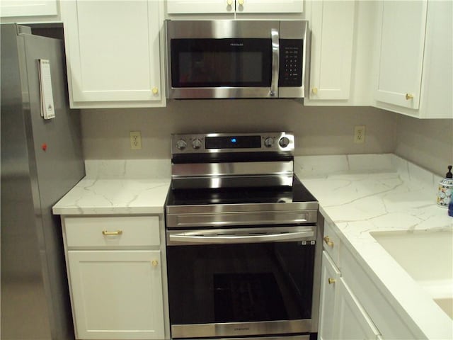 kitchen featuring appliances with stainless steel finishes, light stone countertops, and white cabinets