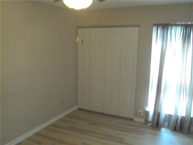 unfurnished bedroom with light hardwood / wood-style floors, a closet, and multiple windows