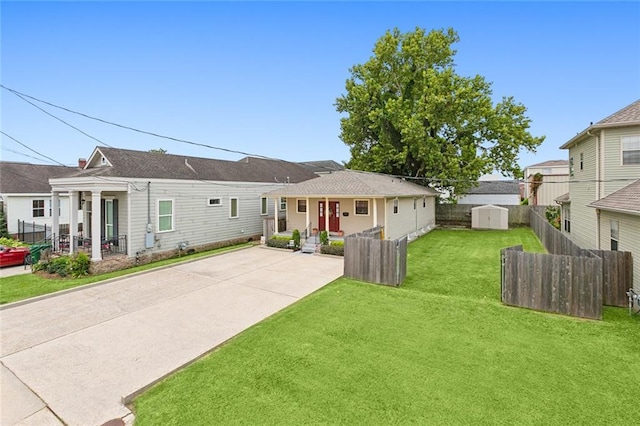 view of front of house with a storage unit, a front yard, a patio area, fence, and an outdoor structure