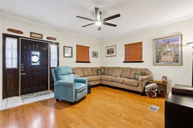 living area with a ceiling fan, visible vents, crown molding, and light wood finished floors