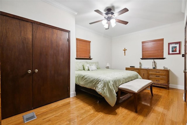 bedroom featuring baseboards, visible vents, crown molding, light wood-style floors, and a closet