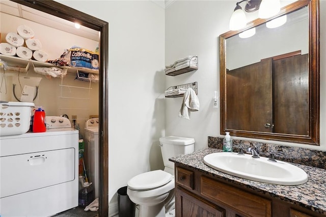 bathroom featuring toilet, washing machine and dryer, and vanity