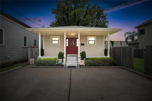 exterior entry at dusk with covered porch and fence