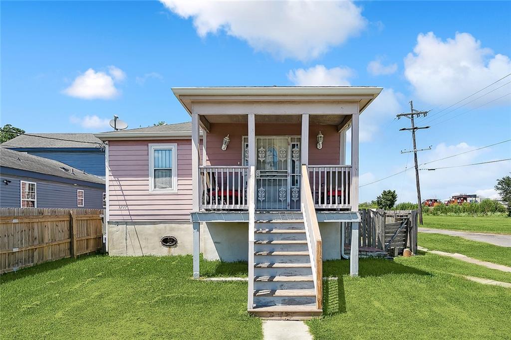 back of property featuring a lawn and covered porch