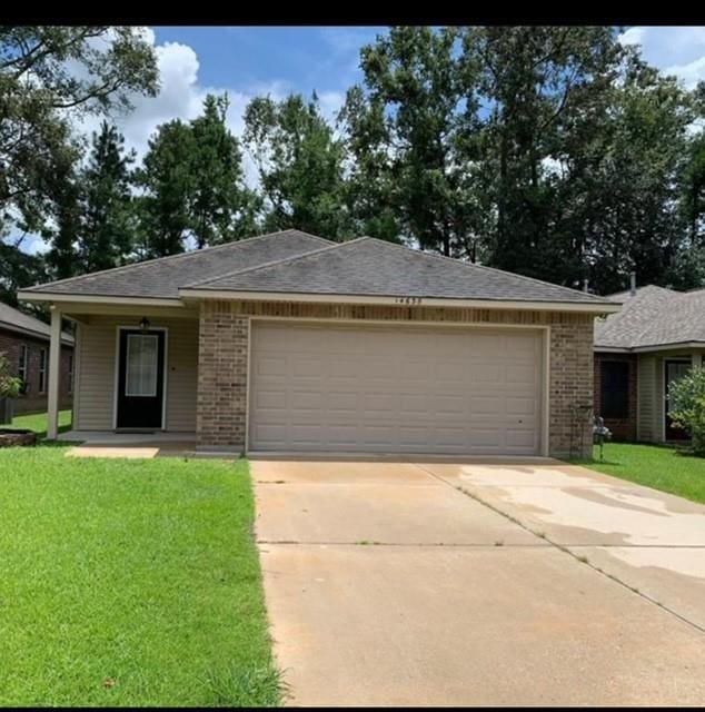 ranch-style home with brick siding, driveway, a front yard, and an attached garage