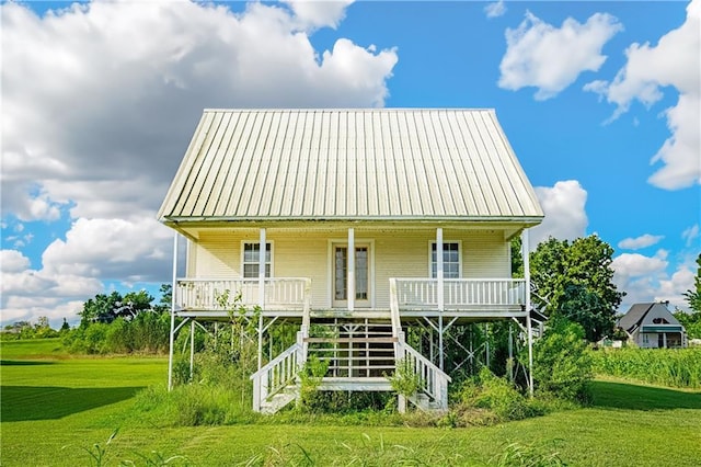 rear view of property with a porch, a standing seam roof, a yard, and metal roof