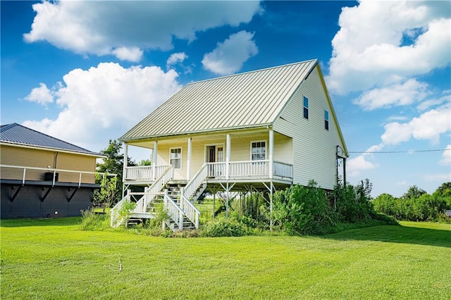 view of front of house featuring a front lawn, metal roof, covered porch, and stairway