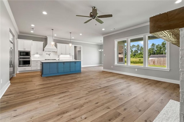 kitchen featuring light wood-type flooring, premium range hood, ceiling fan, hanging light fixtures, and appliances with stainless steel finishes