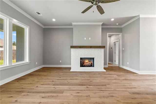 unfurnished living room featuring ceiling fan, a tiled fireplace, ornamental molding, and light hardwood / wood-style flooring