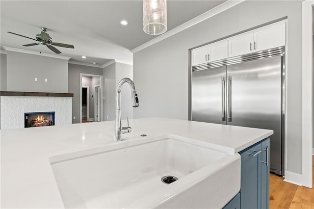 kitchen featuring a fireplace, blue cabinetry, sink, ceiling fan, and stainless steel built in refrigerator