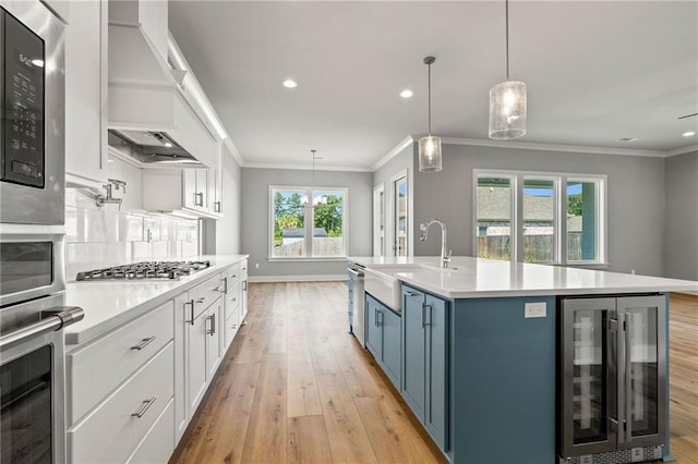 kitchen with white cabinetry, sink, wine cooler, blue cabinets, and a center island with sink