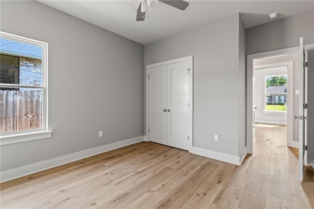 unfurnished bedroom featuring ceiling fan, a closet, and light wood-type flooring