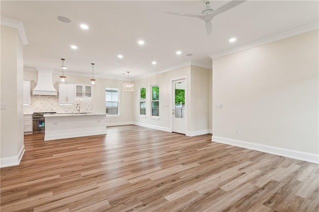 unfurnished living room featuring ceiling fan, light hardwood / wood-style flooring, and ornamental molding