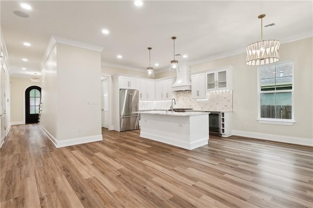 kitchen with light hardwood / wood-style flooring, decorative light fixtures, and stainless steel refrigerator