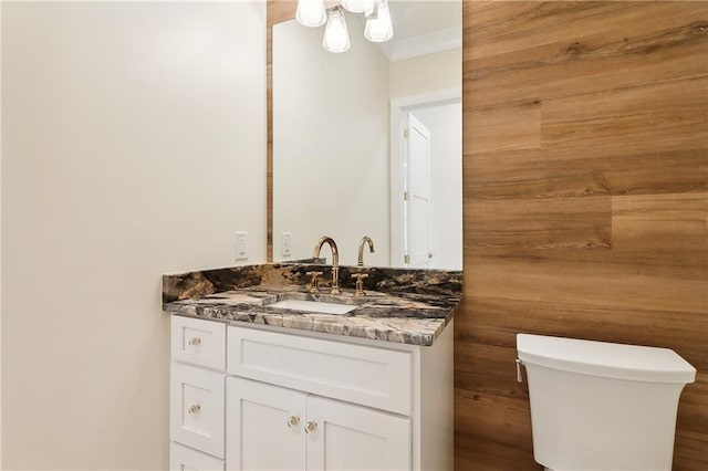 bathroom featuring wood walls, vanity, and toilet