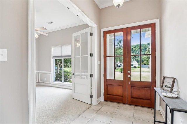 tiled entryway with crown molding, a healthy amount of sunlight, ceiling fan, and french doors