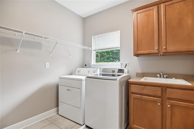 laundry area with cabinets, light tile patterned flooring, sink, and washer and clothes dryer