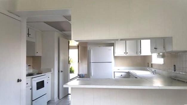 503 Wright Ave, Terrytown, LA 70056 - kitchen featuring a sink, white appliances, light countertops, a peninsula, and white cabinetry