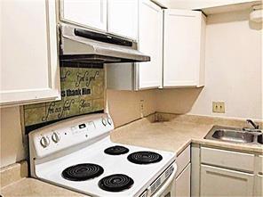 kitchen with electric range, sink, and white cabinetry