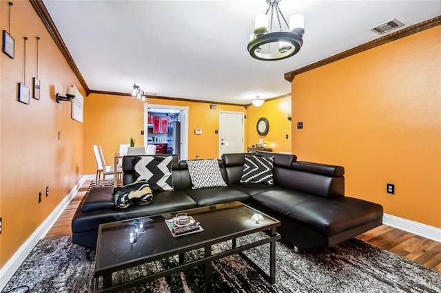 living room with crown molding, a chandelier, and wood-type flooring