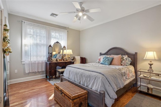 bedroom with ceiling fan, multiple windows, ornamental molding, and hardwood / wood-style flooring