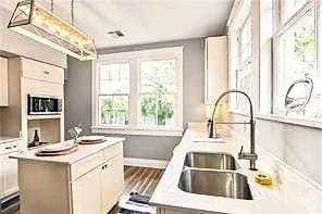 1831 S Dupre St, New Orleans, LA 70125 - kitchen with baseboards, light countertops, a kitchen island, decorative light fixtures, and a sink