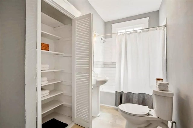 bathroom with toilet, shower / tub combo, and tile patterned floors