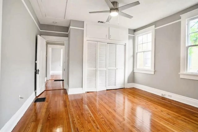 unfurnished bedroom featuring hardwood / wood-style flooring, ceiling fan, and a closet