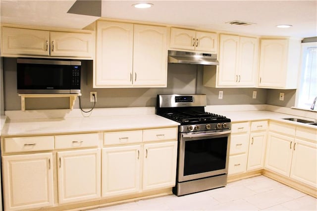 kitchen featuring light tile patterned floors, cream cabinets, stainless steel appliances, and sink