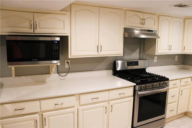 1831 S Dupre St, New Orleans, LA 70125 - kitchen with visible vents, cream cabinetry, appliances with stainless steel finishes, under cabinet range hood, and light countertops