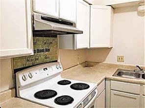 1831 S Dupre St, New Orleans, LA 70125 - kitchen with white cabinets, a sink, light countertops, white range with electric cooktop, and under cabinet range hood