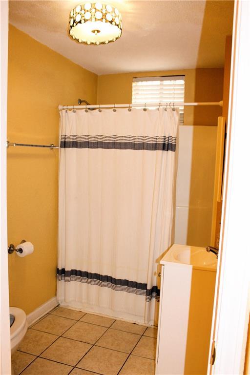 1831 N Miro St, New Orleans, LA 70119 - full bathroom featuring toilet, baseboards, a shower with shower curtain, and tile patterned flooring