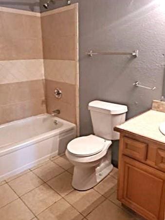 full bathroom with tile patterned flooring, vanity, toilet, and tiled shower / bath combo