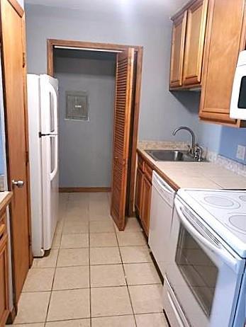 kitchen with sink, light tile patterned floors, and white appliances