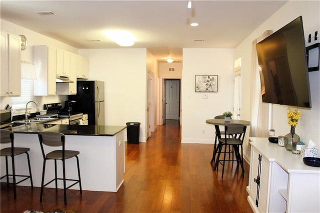 kitchen with stainless steel electric range oven, kitchen peninsula, dark wood-type flooring, a breakfast bar area, and white cabinets