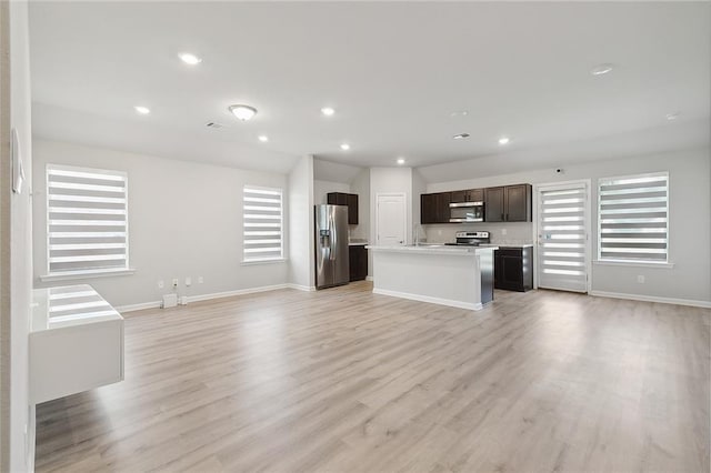 unfurnished living room with recessed lighting, baseboards, light wood-type flooring, and a wealth of natural light