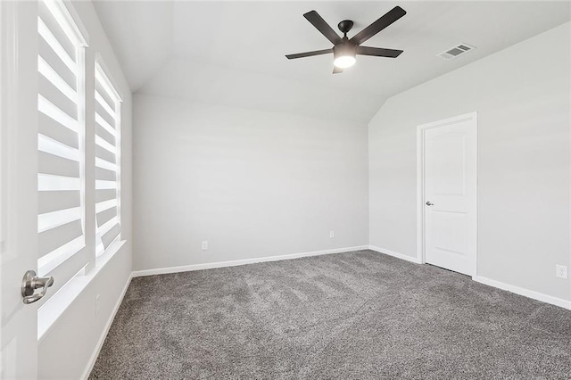 carpeted empty room with visible vents, baseboards, ceiling fan, and vaulted ceiling