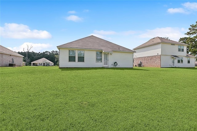 back of property with a yard and central AC