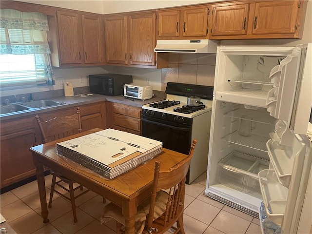 kitchen with tasteful backsplash, gas range gas stove, exhaust hood, light tile patterned floors, and sink