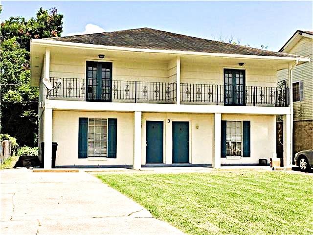 rear view of property with a yard and a balcony