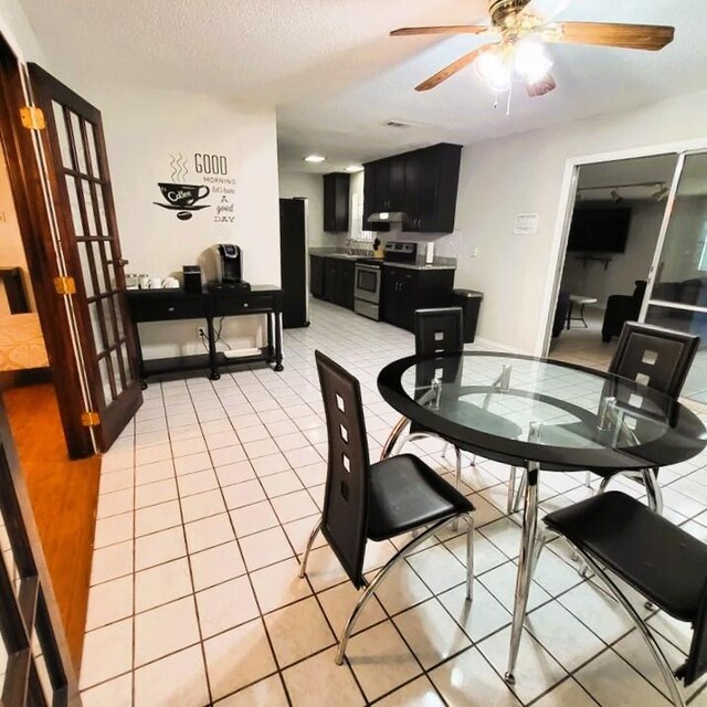 dining area with a textured ceiling, ceiling fan, and light tile patterned flooring