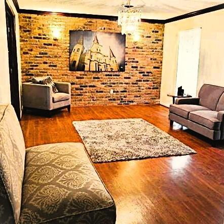 3738 Somerset Dr, New Orleans, LA 70131 - living area featuring crown molding, brick wall, an inviting chandelier, and wood finished floors