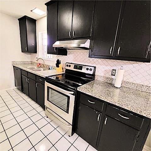 kitchen featuring stainless steel appliances, sink, decorative backsplash, and light tile patterned flooring