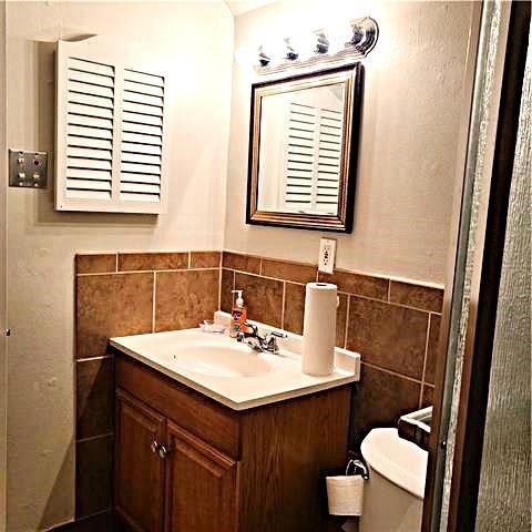 bathroom featuring vanity, toilet, backsplash, and tile walls