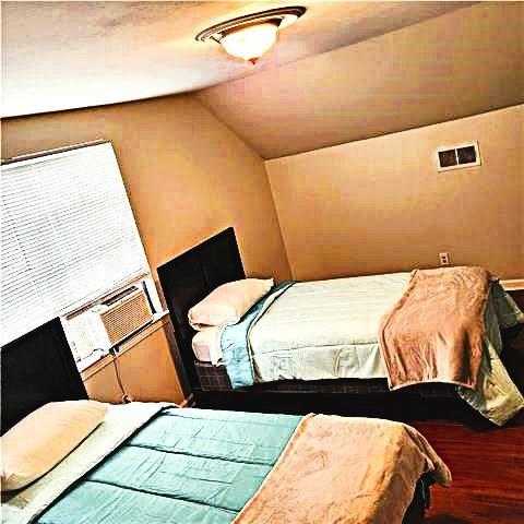 bedroom with cooling unit, hardwood / wood-style flooring, and vaulted ceiling