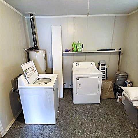 laundry area with crown molding, washer and clothes dryer, and water heater