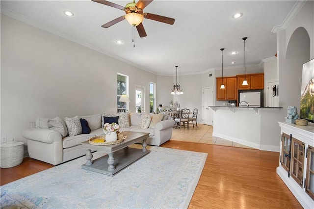 living room with ceiling fan, crown molding, and light hardwood / wood-style floors