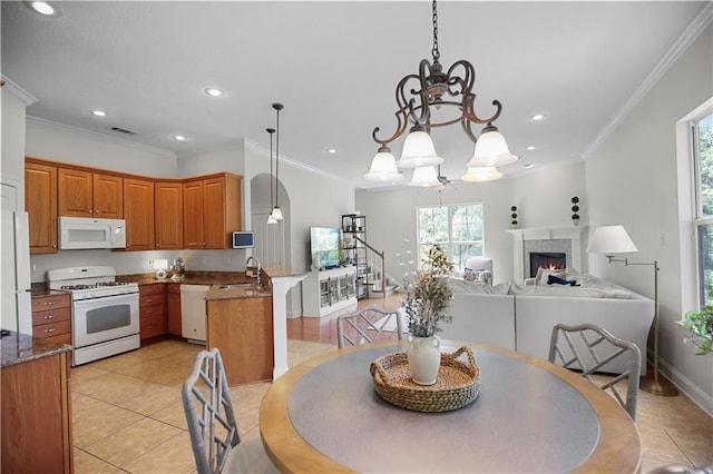 tiled dining room featuring sink, crown molding, and a chandelier